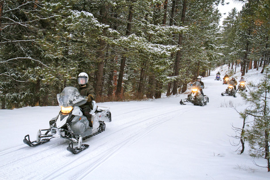 group snowmobiling on a trail